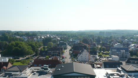 Aerial-drone-flying-forward-above-resort-hotel-and-houses-buildings-streets-in-Scharbeutz,-Germany,-day